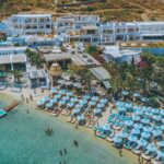 Drone view of Psarou beach and famous Mykonos restaurants by boat