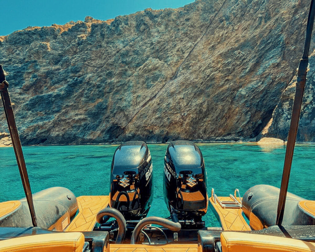 A modern Don Blue Yachting RIB boat anchored near the vertical cliffs of Dragonisi