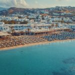 Aerial view of a packed Ornos beach, highlighting the contrast between traditional Mykonos sunbed prices vs private boat freedom.