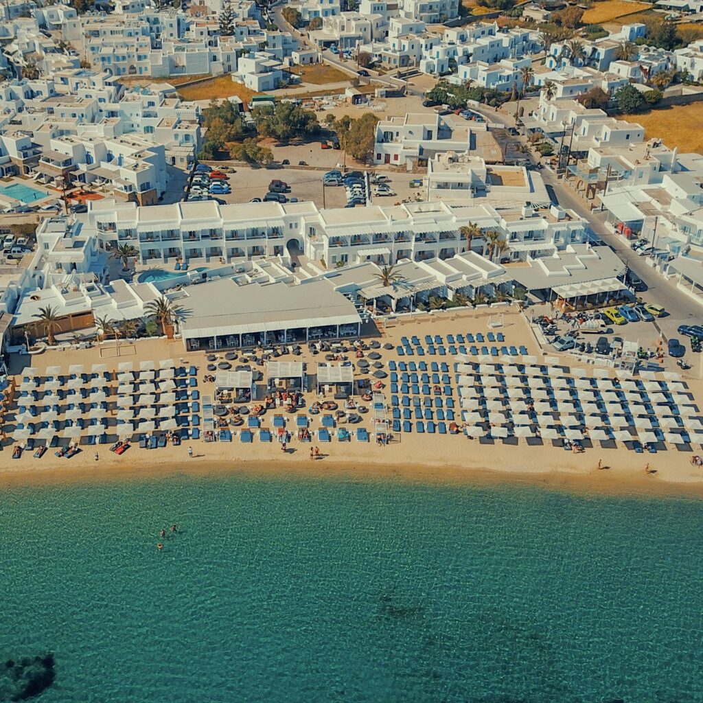 Overhead shot of a bustling Mykonos beach, a visual reminder to compare Mykonos sunbed prices vs private boat luxury and privacy.