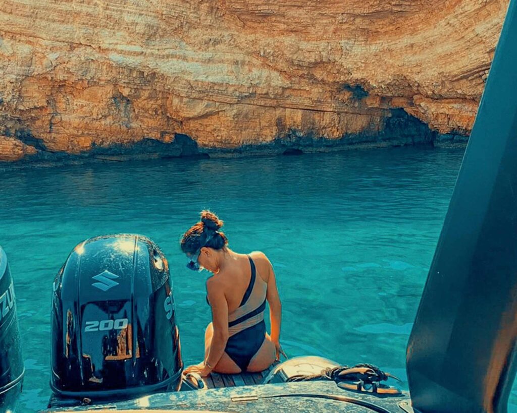 A woman sitting at the back of a Don Blue Yachting private boat soaking in the Aegean views — because the Paros vs Mykonos question is best answered from the water