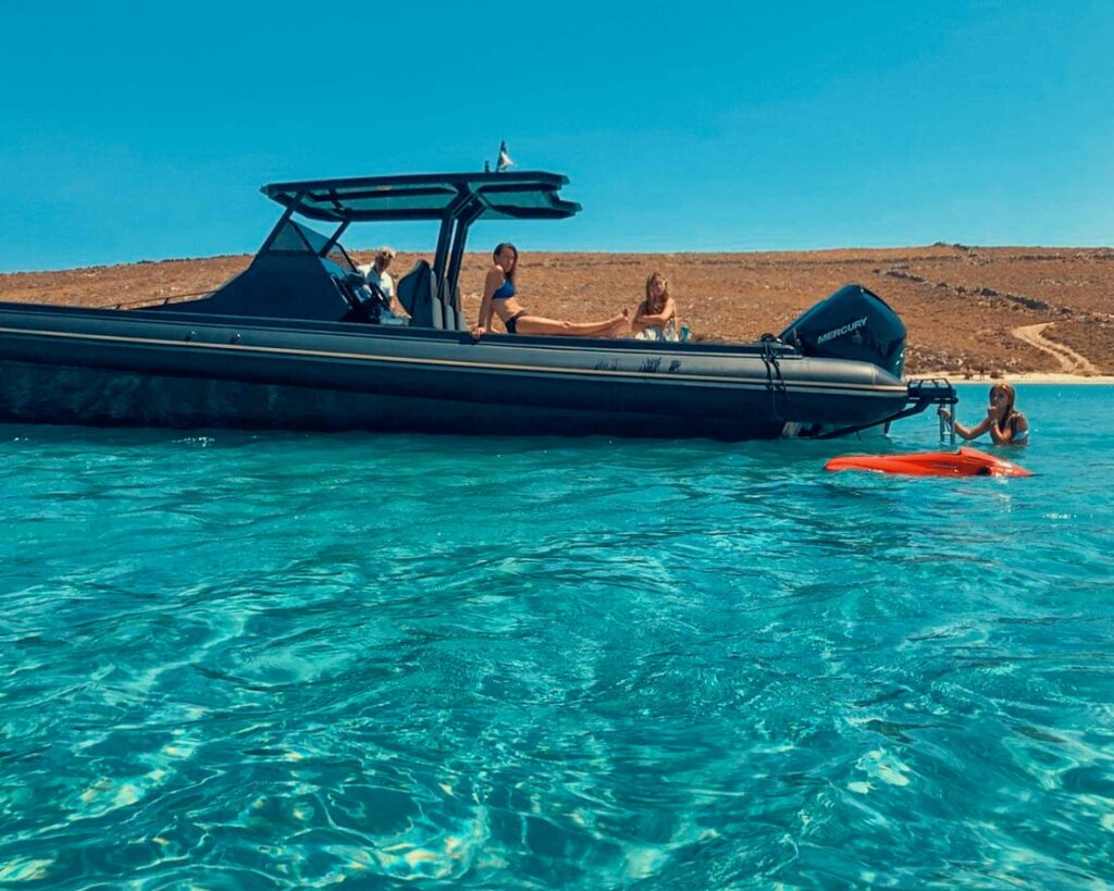 Guests relaxing on the side of a Don Blue Yachting private boat enjoying the open Aegean — the effortless way to avoid crowds in Mykonos and make the most of every hour on the water.