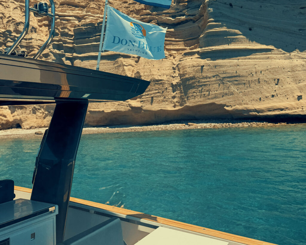 View from a boat showcasing the steep cliffs and isolated beaches of southern Antiparos coastline, featured in the article about Evan Fournier in Greece.