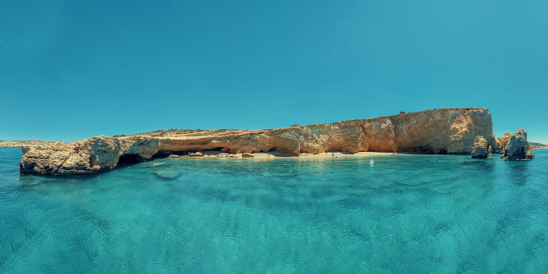 The dramatic vertical cliffs and rock formations of the eastern face of Glaronisi Koufonisia seen from a Don Blue Yachting private boat